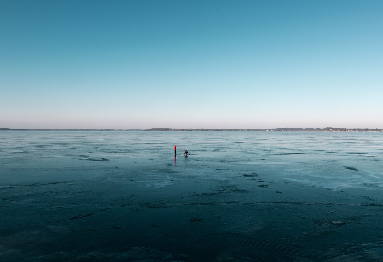 After a week of warmer days the snow melted away from the frozen lake. People were ice fishing on the thinner ice.