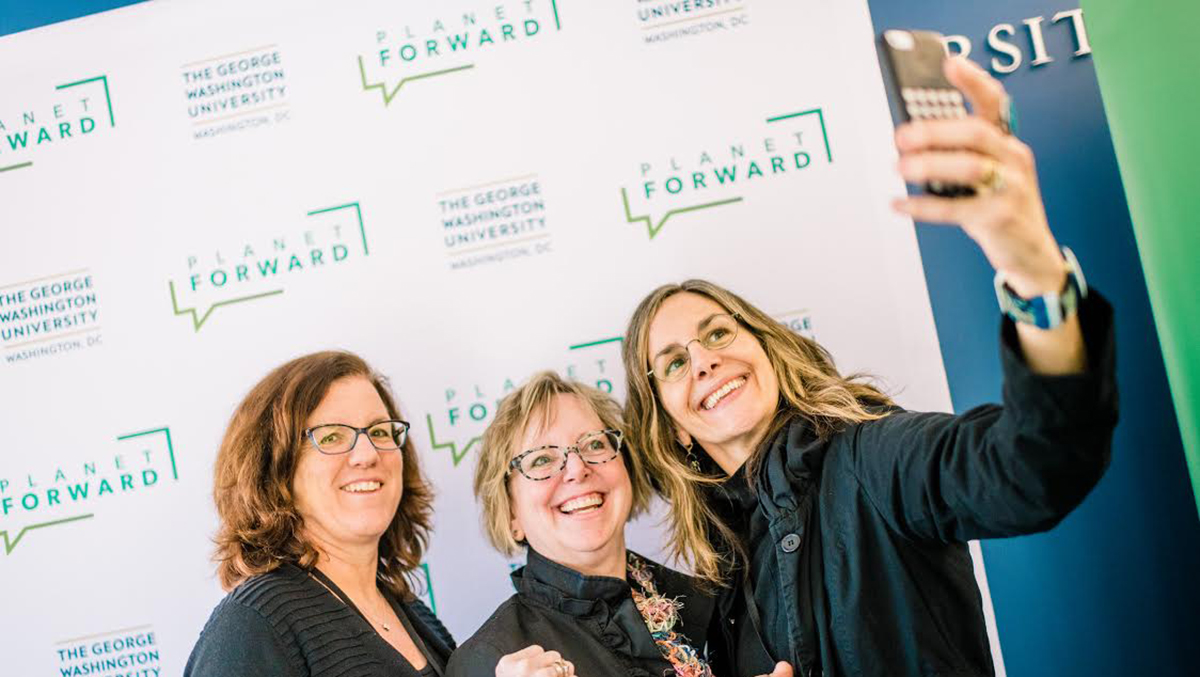 Attendees take a selfie at the Summit in front of the Planet Forward wall.