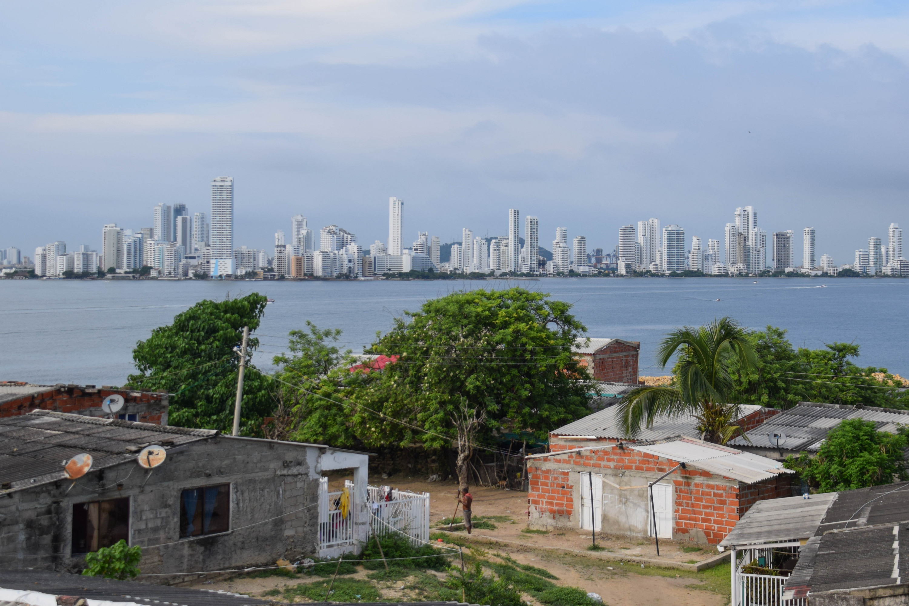 The difference in life from the sea-sufficient Tierra Bomba, and the high-rises of Boca Grande are evident in this photo with a farmer in the foreground tending to his garden and the high-rises and clear beaches in the distance.