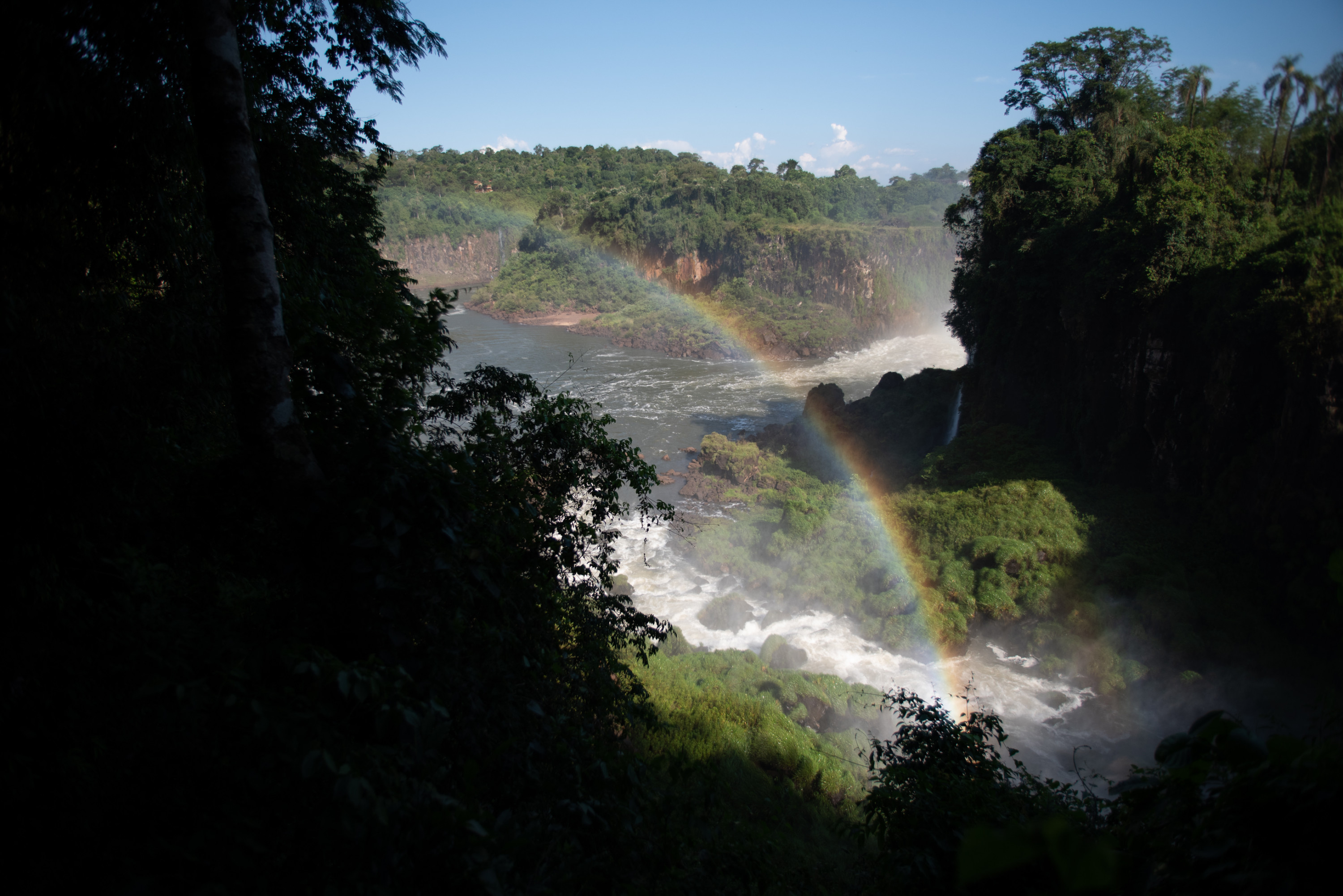 A rainbow stretches across the mist of waterfalls in Iguazú National Park.