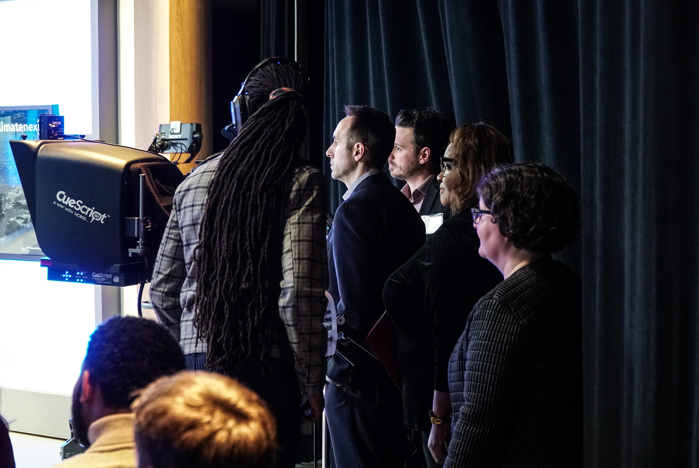 Panel guests line up just off camera, getting ready to take the stage.