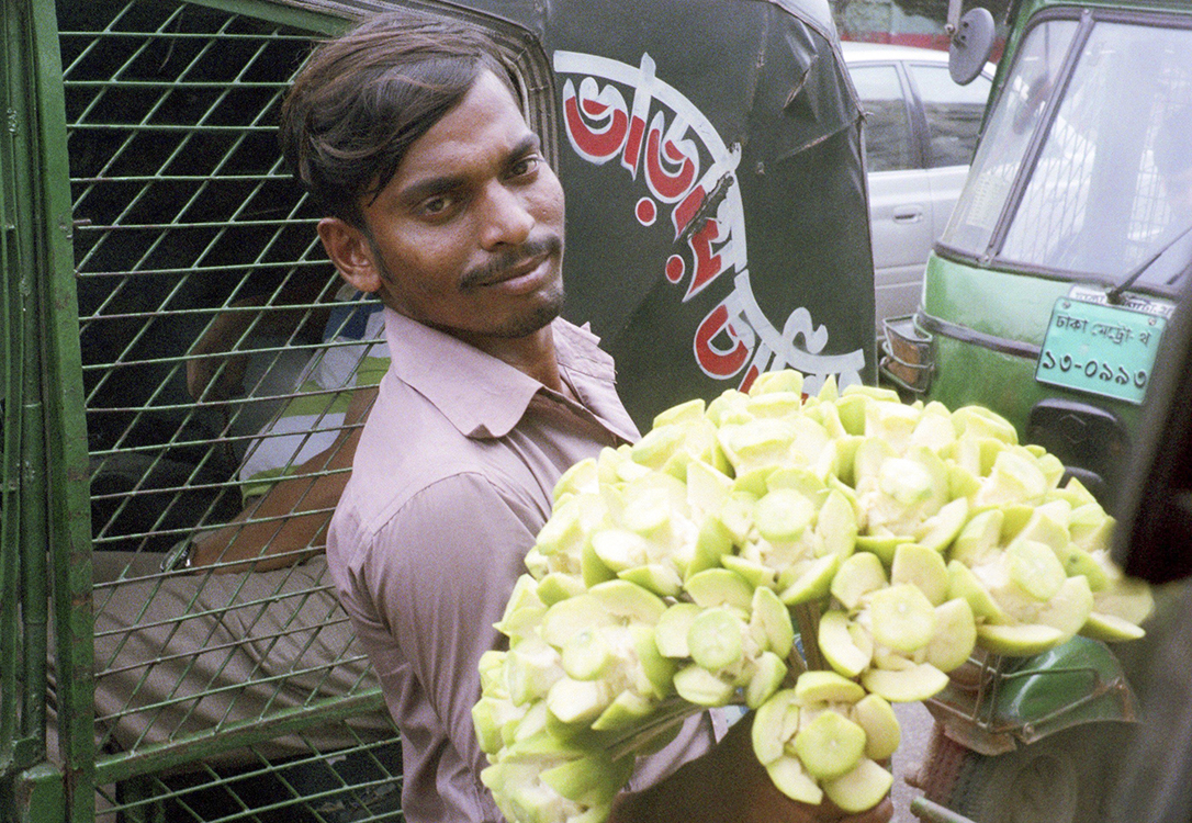 A man sells carved guava to cars trapped in traffic.