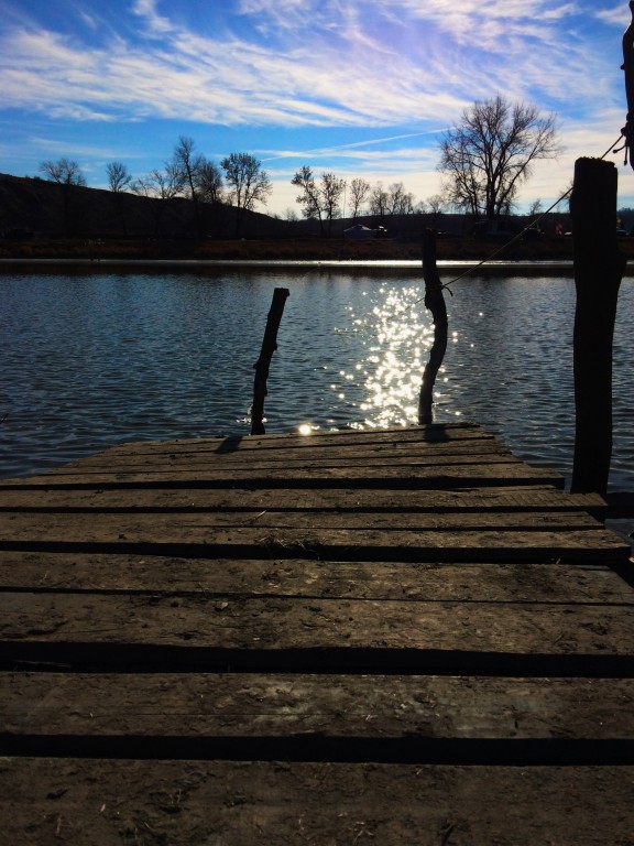 Riverbank: A makeshift dock into the river rests along the bank. The midday sun allows the water to sparkle, a peaceful moment of solitary enjoyment of the water so ardently protected.