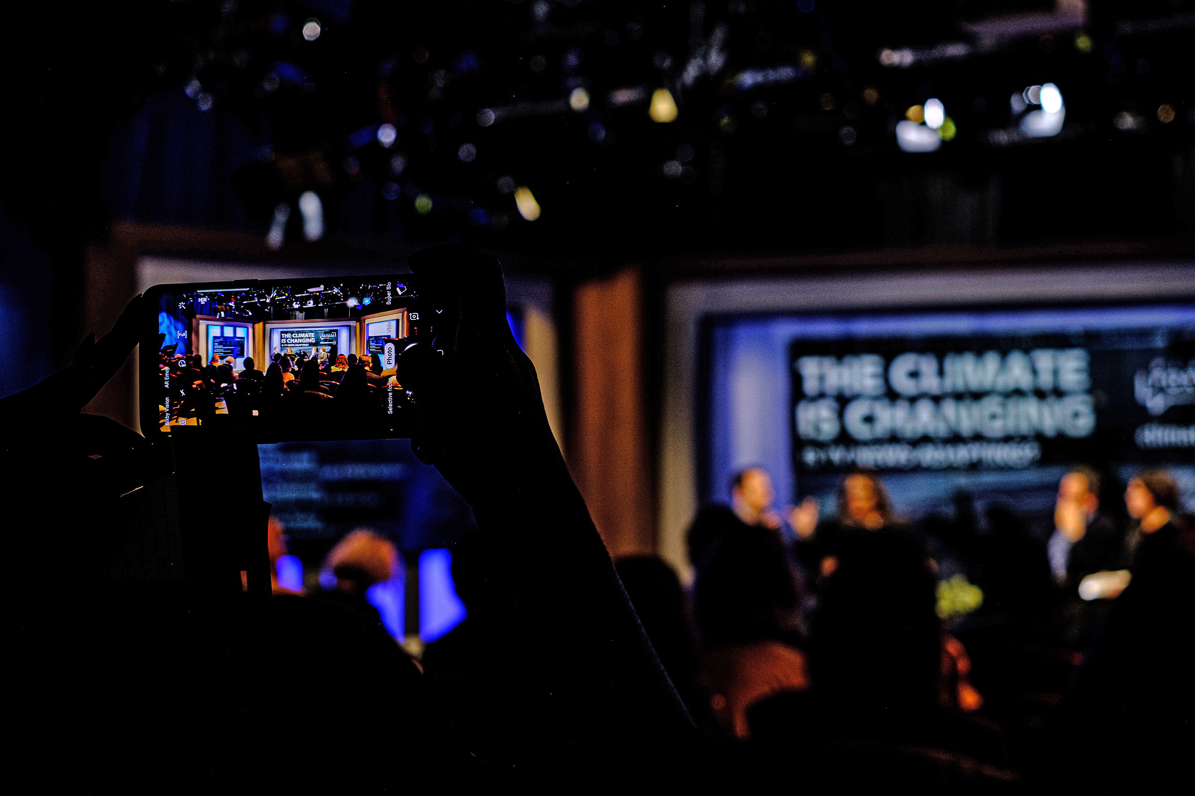 A Climate Nexus staffer snaps a shot of the event from their phone.