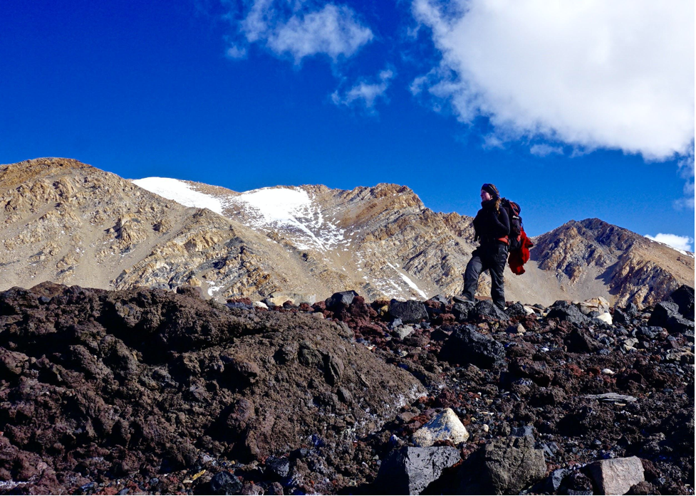 Researcher Laura Mattas, a member of an increasingly diverse generation of Antarctic scientists, climbs rocky terrain while carrying a large pack. “The rocks that we’re dating on those landforms, once they’re deposited by a glacier, they start accumulating this beryllium and so we can get the absolute age based on that,” Mattas said. (Photo courtesy Laura Mattas)