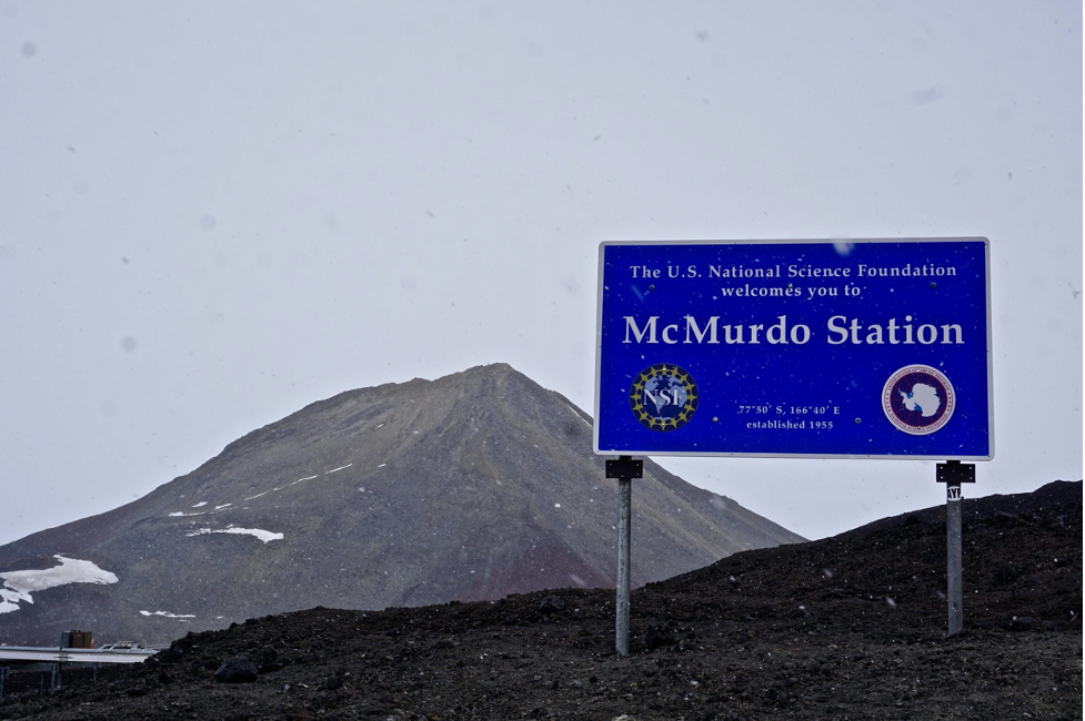 A sign on a rocky hill welcoming visitors to McMurdo Station. McMurdo Station is located on Ross Island, at the southernmost point of solid ground accessible by ship, and is the logistical center of the U.S. Antarctic Program, operated by the National Science Foundation. (Photo courtesy Laura Mattas)
