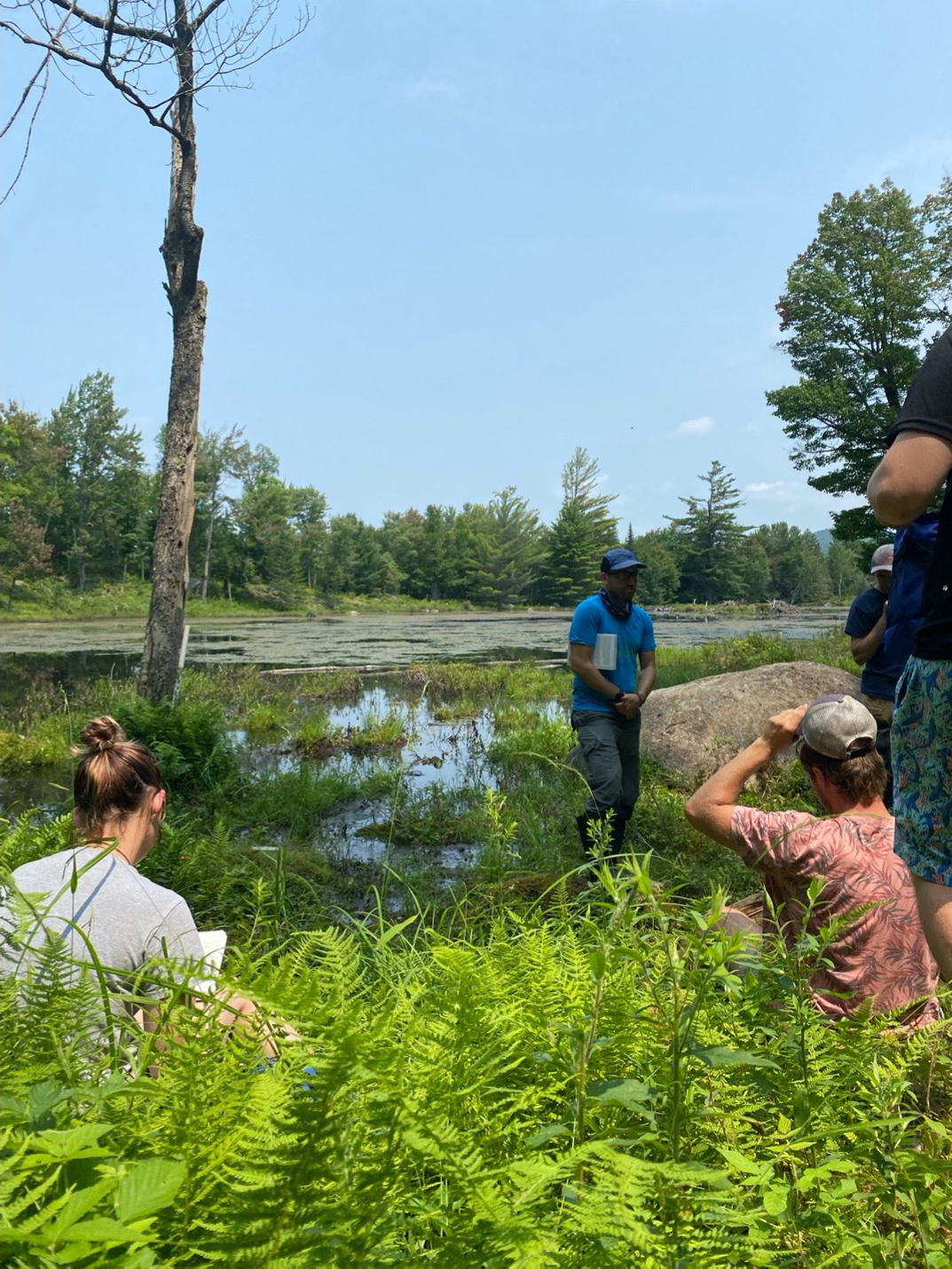 Herpetology professor giving a lecture about call surveys, near a pond.