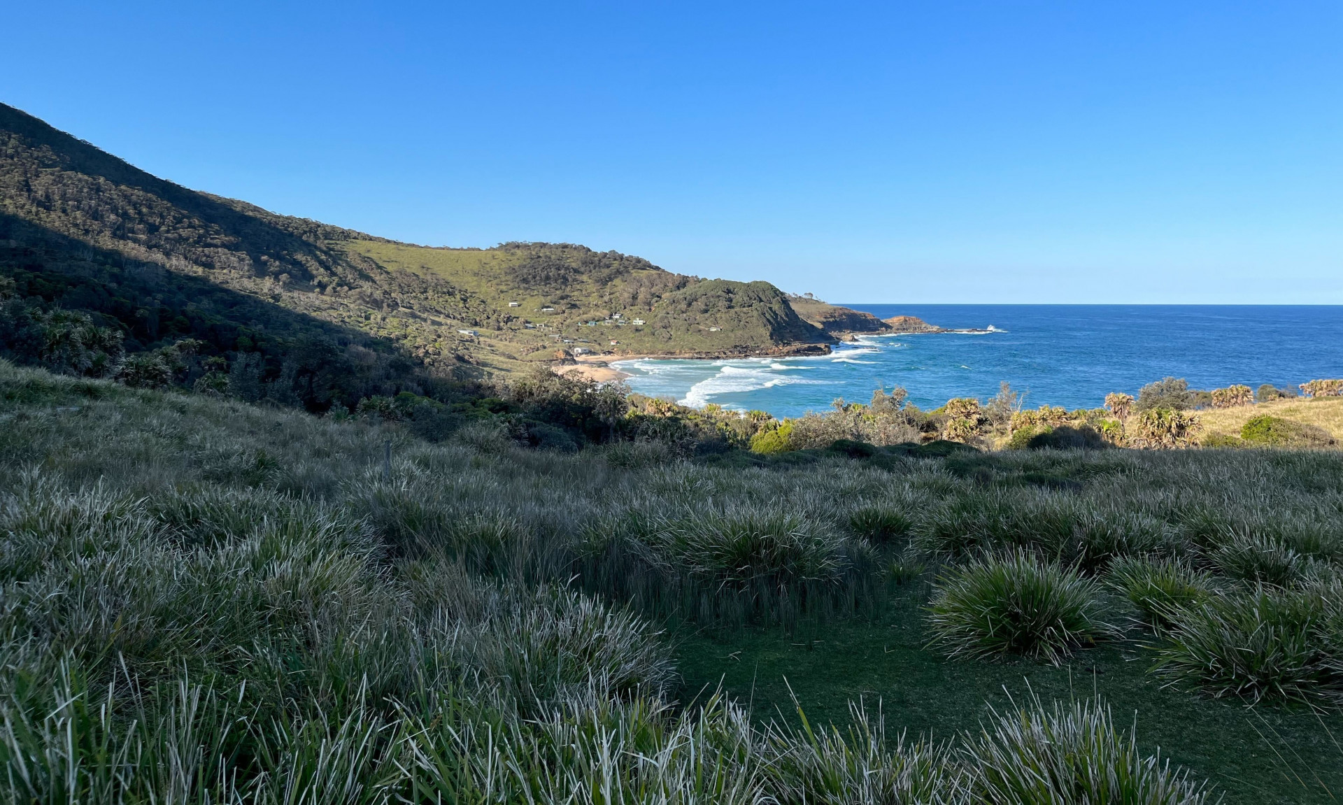 A green valley dips down towards the coastline.