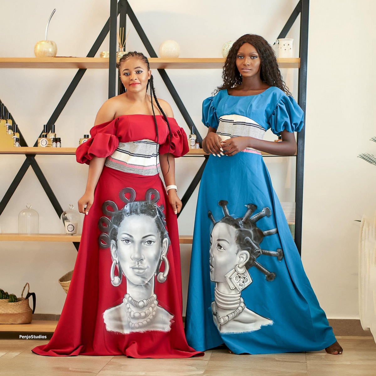 Two women pose in colorful dresses.