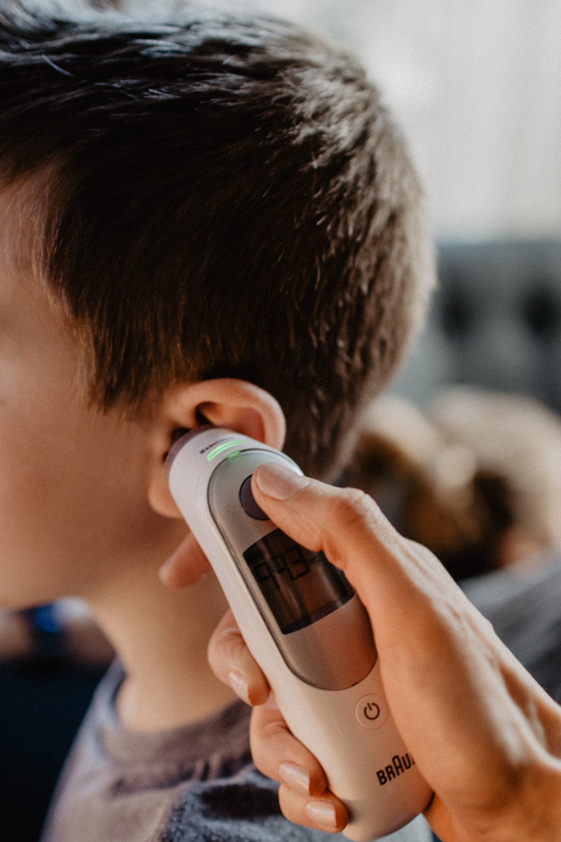A thermometer is held to a child's ear. Extreme heat is affecting more and more children. 