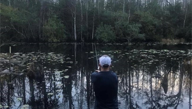 A man fishes at a swampy stream in Georgia.