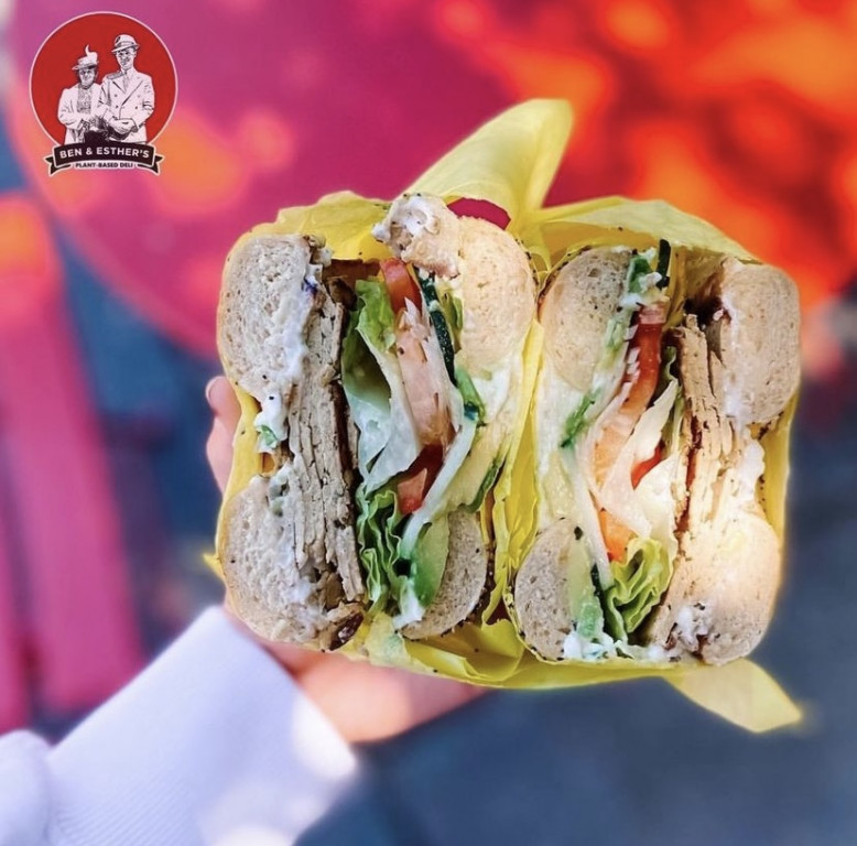A bagel sandwich is stuffed with vegan meet and other fixings.
