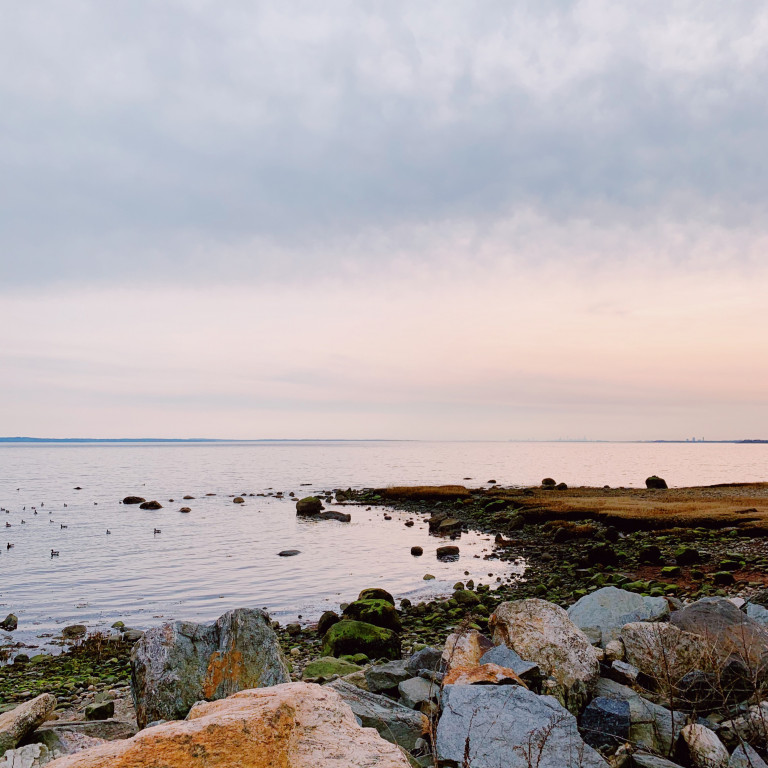 A rock peninsula extends in the Long Island Sound at sunset. This area has been hit by Hurricane Sandy and Ida in recent memory. 