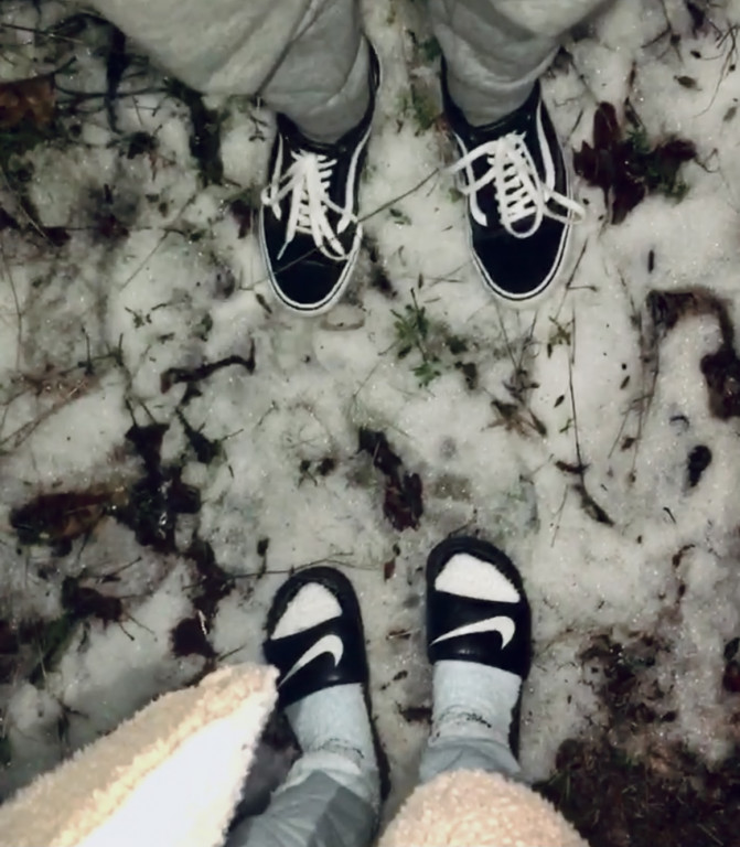 An image of two pairs of feet standing on a shallow dusting of snow. 