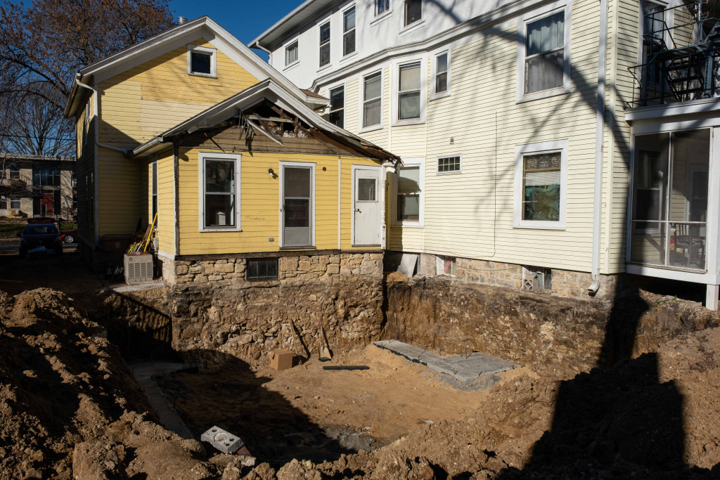 A large excavated area of dirt behind a yellow house at a housing co-op.