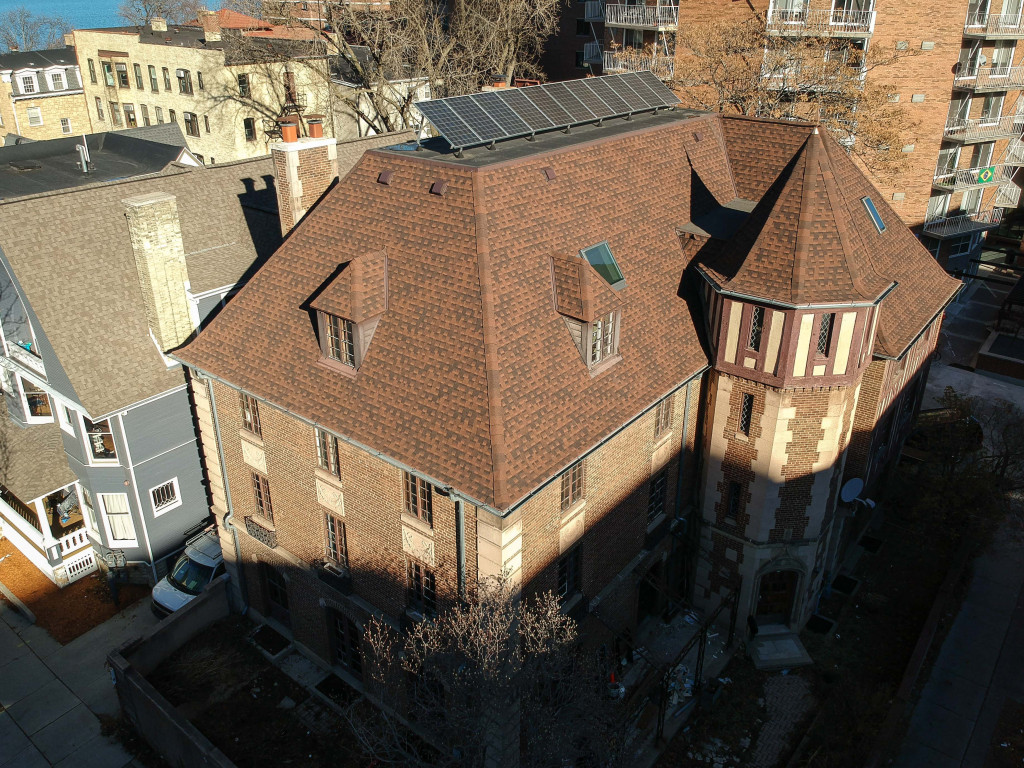 A large brown building with solar panels on the roof seen from above.