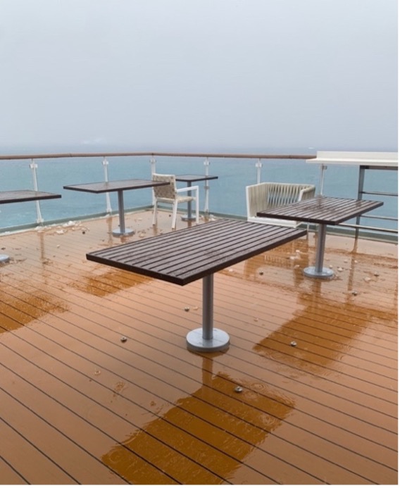 Rain falls on tables and chairs on a ship deck